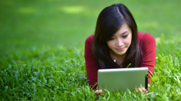 Young beautiful woman on the lawn reading